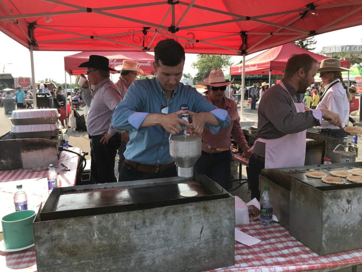 Calgary councillor and mayoral hopeful Jeromy Farkas pours pancakes on the griddle at a Stampede breakfast on July 14, 2021.