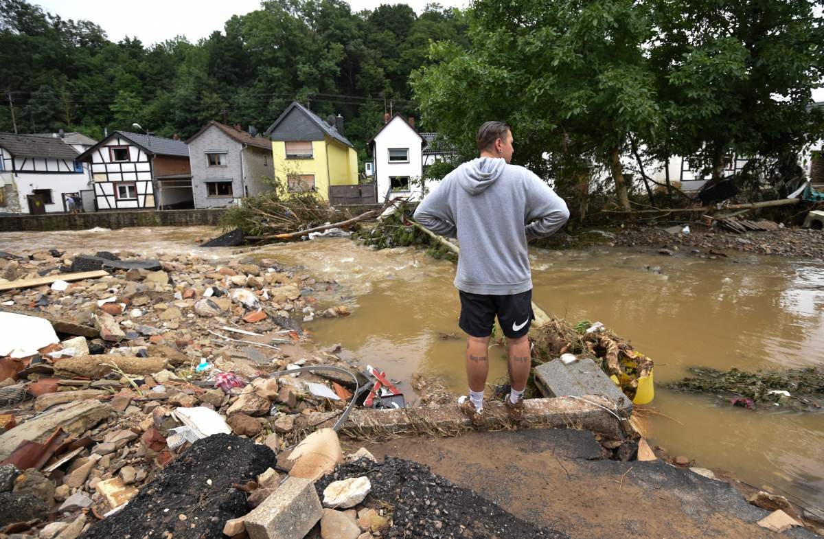 A photo taken on July 16, 2021 shows a man standing at a flooded intersection near the Erft river in Iversheim near Bad Muenstereifel, western Germany, after heavy rain hit parts of the country, causing widespread flooding.