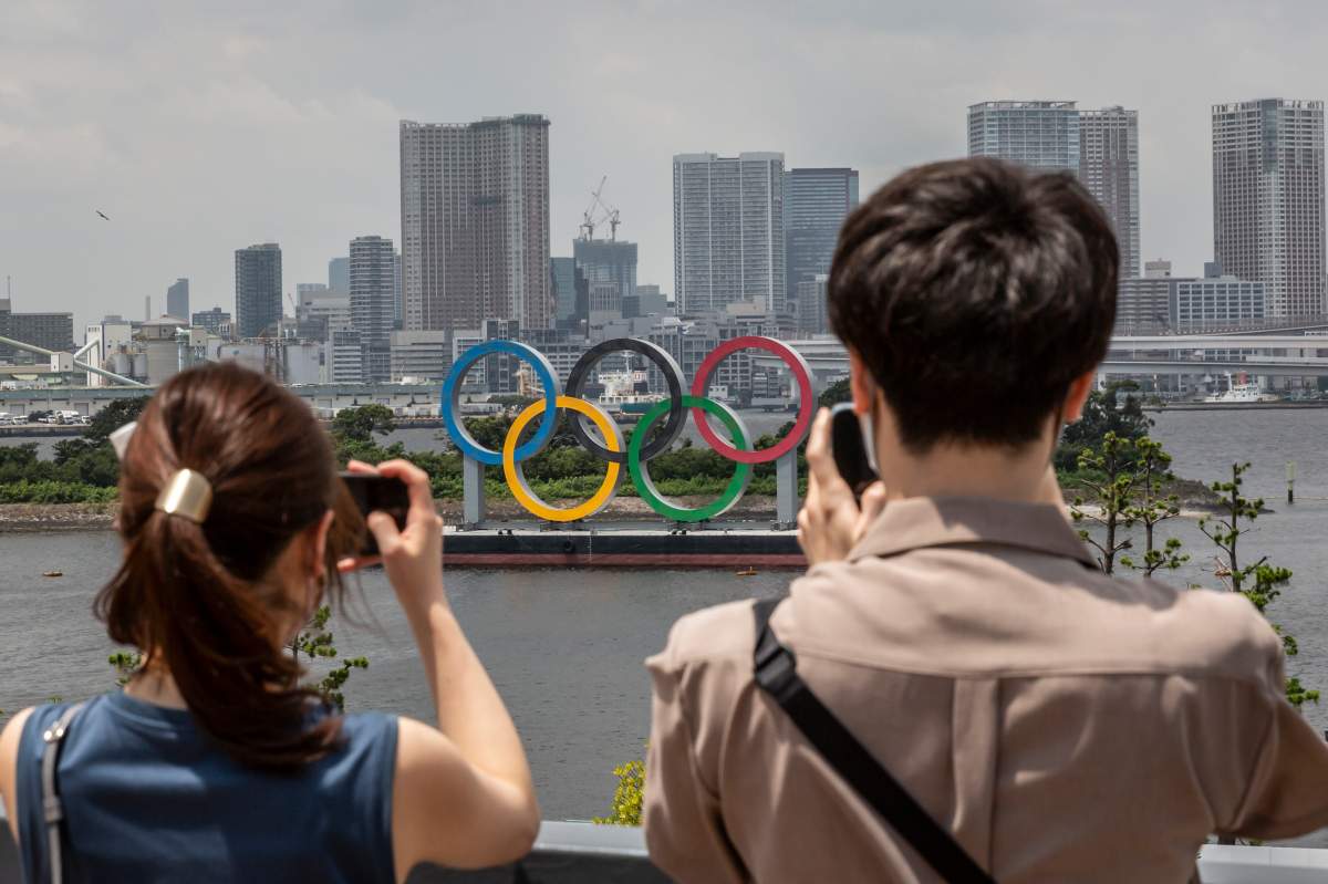 People take pictures of Olympics rings on July 28, 2021 in Tokyo, Japan. Fans have been barred from most Olympic events due to the Covid-19 pandemic, which also caused the Games' yearlong postponement.