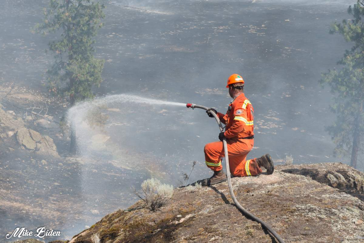 A firefighter douses hot spots at the Thomas Creek wildfire east of Skaha Lake.
