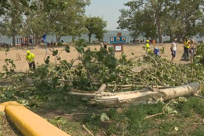 Crews pick up fallen branches and debris left on the beach following a storm Sunday night in Regina Beach. (Derek Putz / Global News)
