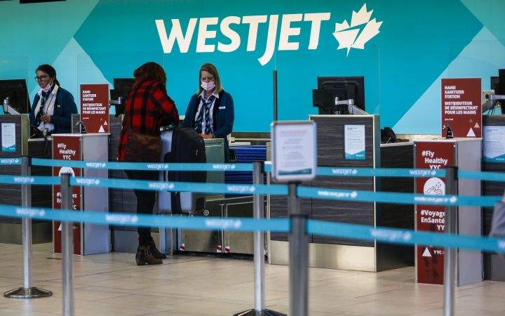 A passenger checks in at a Westjet counter at  the Calgary Airport in Calgary, Alta., Friday, Oct. 30, 2020, amid a worldwide COVID-19 pandemic. 