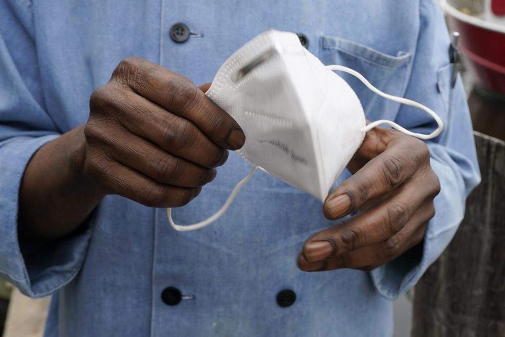 A person is shown holding a face mask. 