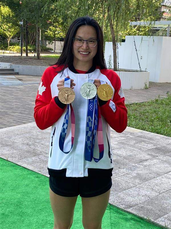 London Ont. swimmer Maggie Mac Neil, 21, holding her three Olympic medals  she won at the Tokyo 2020 Olympics.