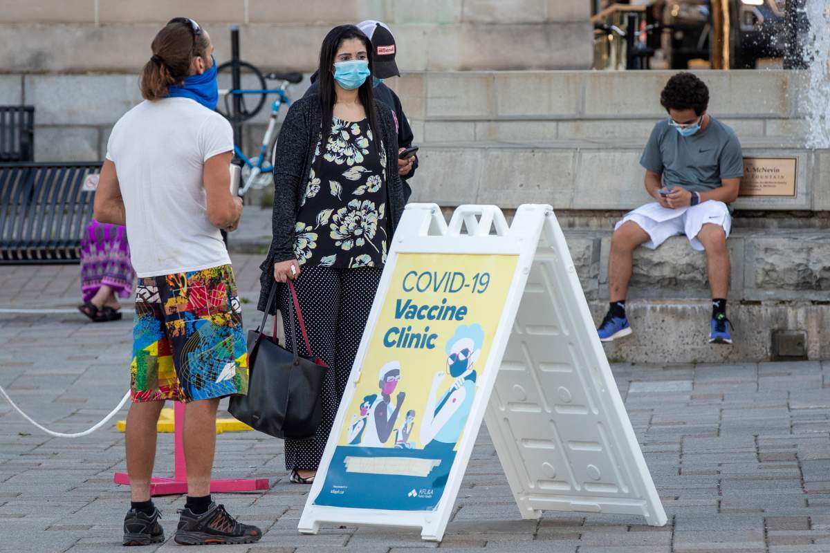 People wear masks as they wait at a COVID-19 walk-in vaccine clinic in Kingston, Ontario on Thursday August 12, 2021. THE CANADIAN PRESS IMAGES/Lars Hagberg.