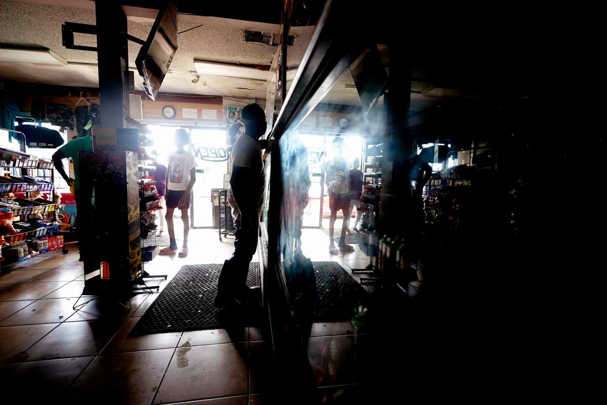 Customers shop in the dark at a convenience store after the effects the effects of Hurricane Ida knocked out power in the area, Monday, Aug. 30, 2021, in Nhew Orleans, La. (AP Photo/Eric Gay)