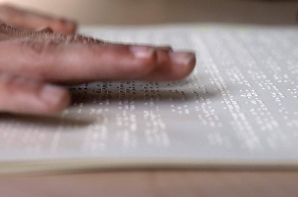In this Tuesday, Oct. 17, 2017 photo proofreader Georgie Sydnor runs her fingers over braille at the National Braille Press in Boston. 