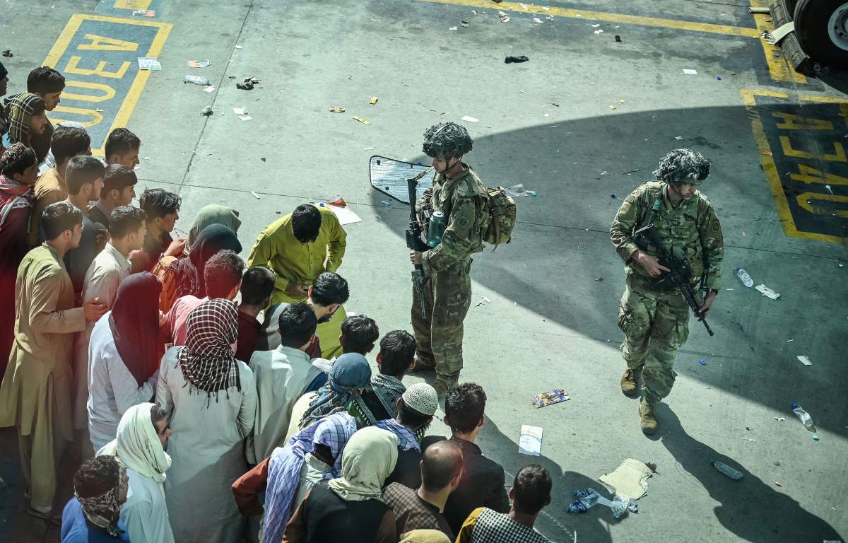 U.S. soldiers stand guard as Afghan people wait at the Kabul airport in Kabul on Aug. 16, 2021.