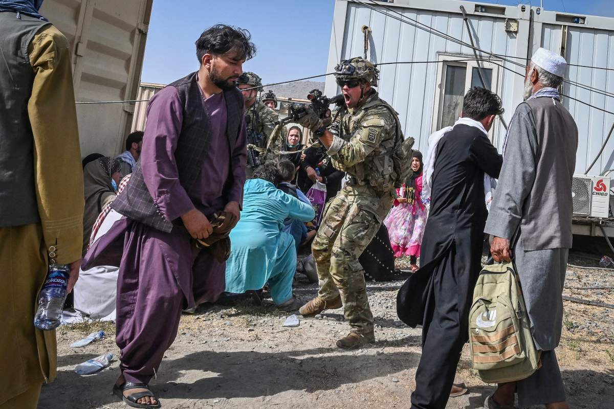 A U.S. soldier (C) point his gun towards an Afghan passenger at the Kabul airport in Kabul on Aug. 16, 2021, after a stunningly swift end to Afghanistan’s 20-year war, as thousands of people mobbed the city’s airport trying to flee the group’s feared hardline brand of Islamist rule.
