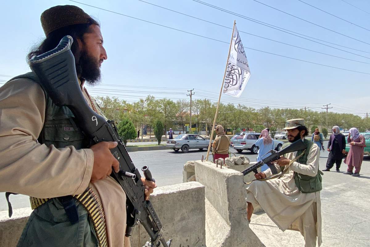 Taliban fighters stand guard at an entrance gate outside the Interior Ministry in Kabul on Aug. 17, 2021.