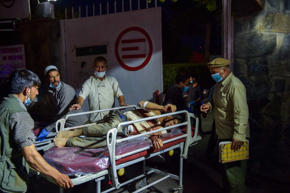 Medical and hospital staff bring an injured man on a stretcher for treatment after two powerful explosions, which killed at least six people, outside the airport in Kabul on Aug. 26, 2021.