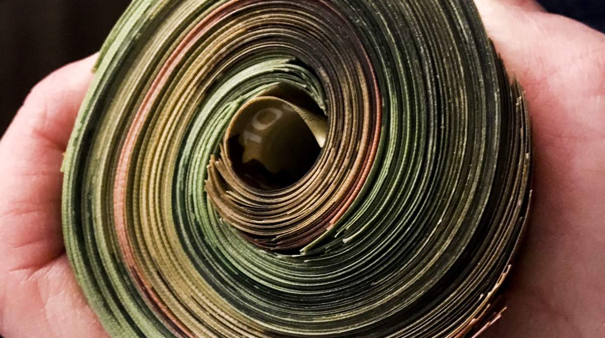 A person holding a wad of cash in this stock image.