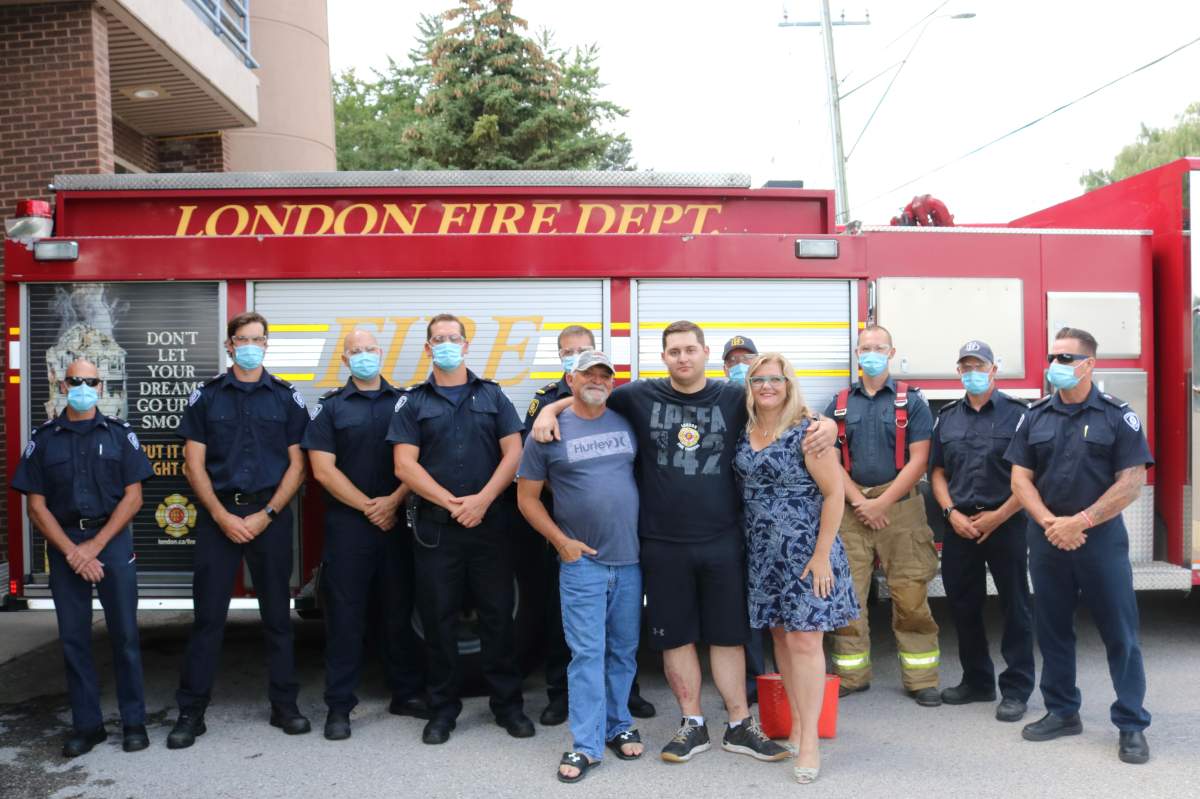 A man stands between his mother and father in front of firefighters.