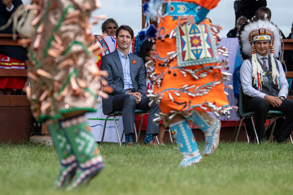 Prime Minister Justin Trudeau, left, and Chief Cadmus Delorme watch dancers during a ceremony celebrating the signing of a transfer of control over children in care to the community, in Cowessess First Nation, Sask., Tuesday, July 6, 2021.  THE CANADIAN PRESS/Liam Richards.