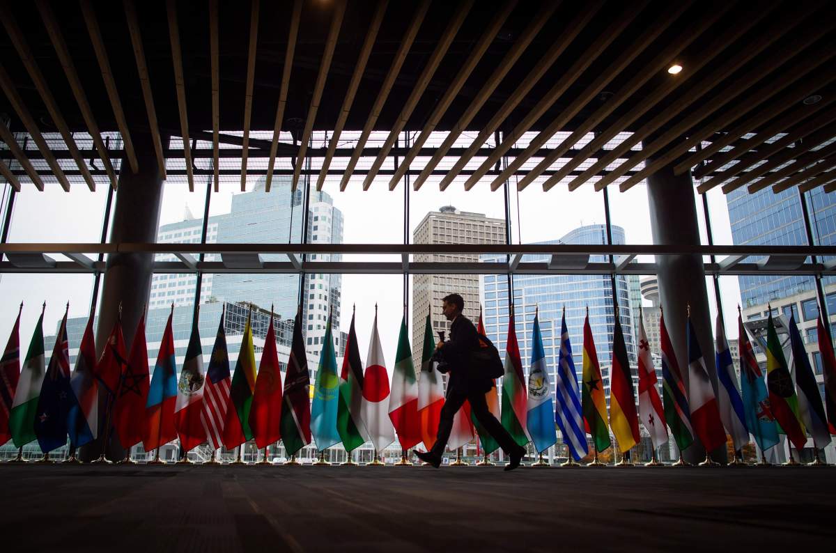 A man walks past the flags of participating nations at the 2017 United Nations Peacekeeping Defence Ministerial conference in Vancouver, B.C., on Tuesday November 14, 2017. The two-day conference is largest gathering of defence ministers dedicated to UN peacekeeping. 