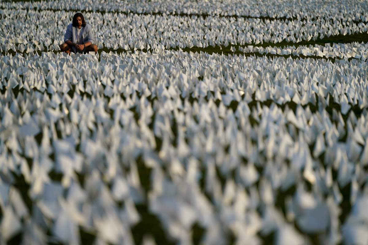 A person looks at white flags that are part of artist Suzanne Brennan Firstenberg’s temporary art installation, “In America: Remember,” in remembrance of Americans who have died of COVID-19, on the National Mall in Washington, Friday, Sept. 17, 2021. The installation consists of more than 630,000 flags. (AP Photo/Brynn Anderson)
