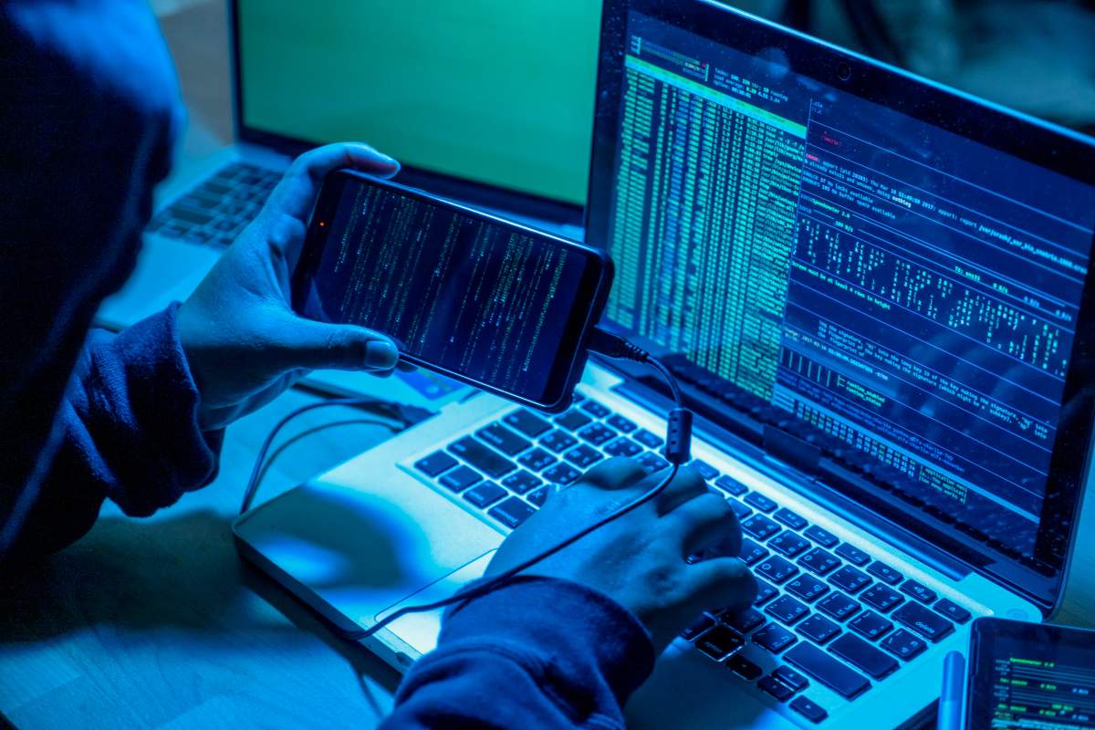 Hacker with computers in dark room. 