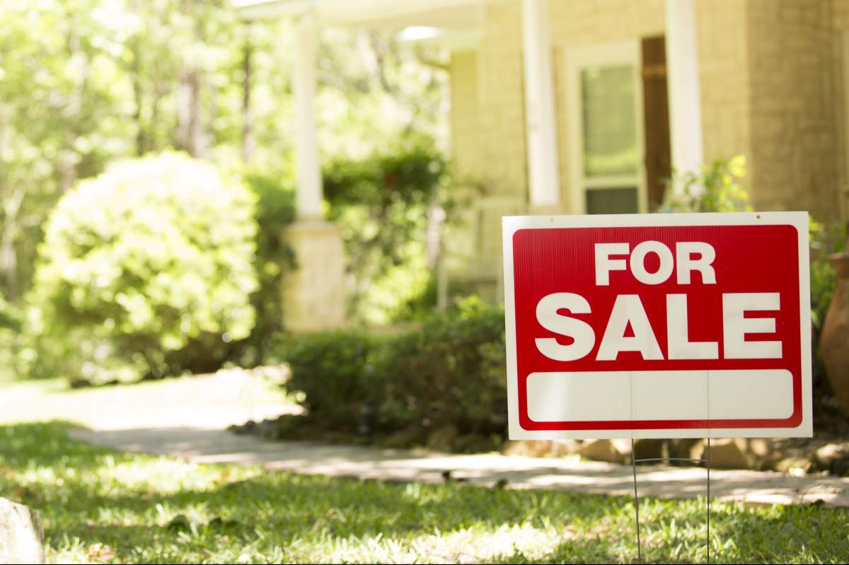 Home for sale with real estate sign in spring or summer season.