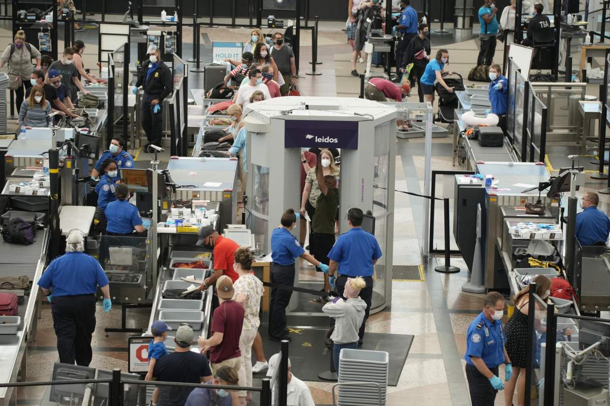 Travelers wear face coverings in the line for the south security checkpoint in the main terminal of Denver International Airport Tuesday, Aug. 24, 2021, in Denver. (AP Photo/David Zalubowski)