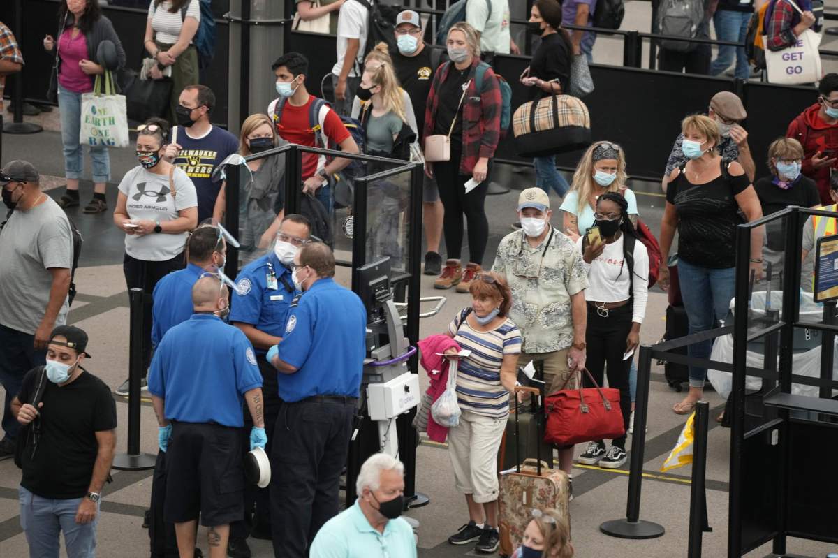 Travelers wear face coverings in a security checkpoint line in the main terminal of Denver International Airport Tuesday, Aug. 24, 2021, in Denver. (AP Photo/David Zalubowski)