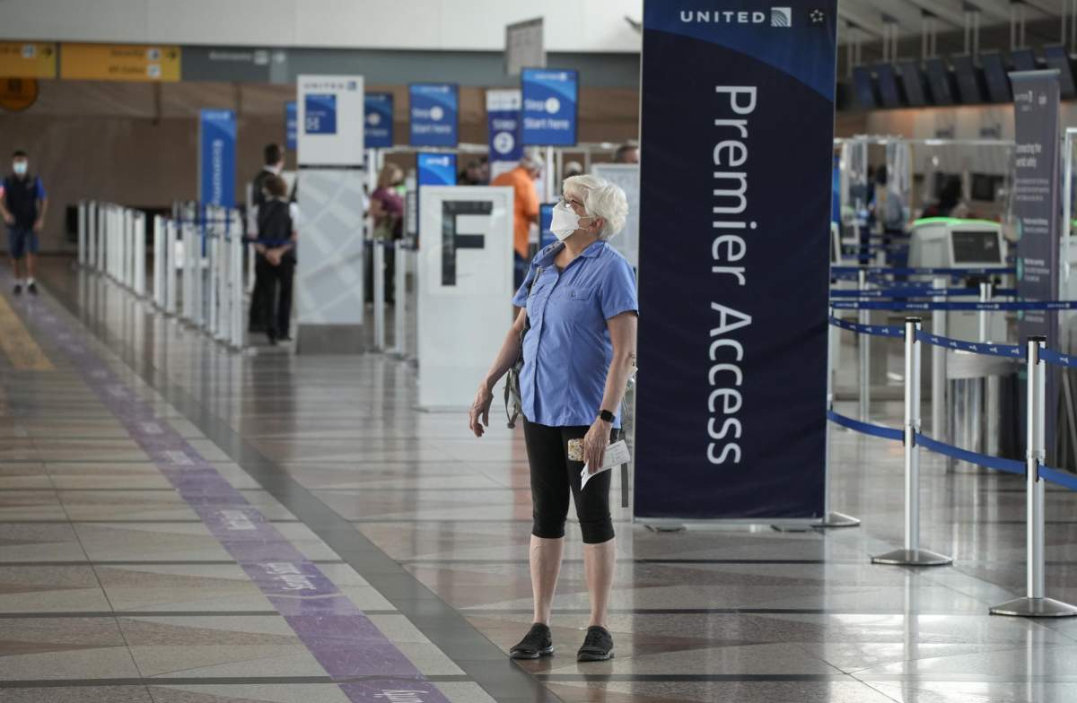 A lone traveler wears a face covering as she stops to check the departure monitors across from the United Airlines ticketing counter in the main terminal of Denver International Airport Tuesday, Aug. 24, 2021, in Denver. (AP Photo/David Zalubowski)