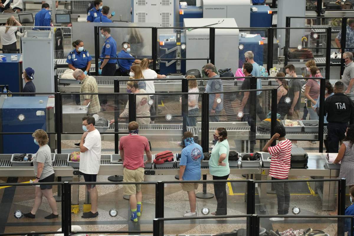 Travelers wear face coverings in the queue for the north security checkpoint in the main terminal of Denver International Airport Tuesday, Aug. 24, 2021, in Denver. (AP Photo/David Zalubowski)