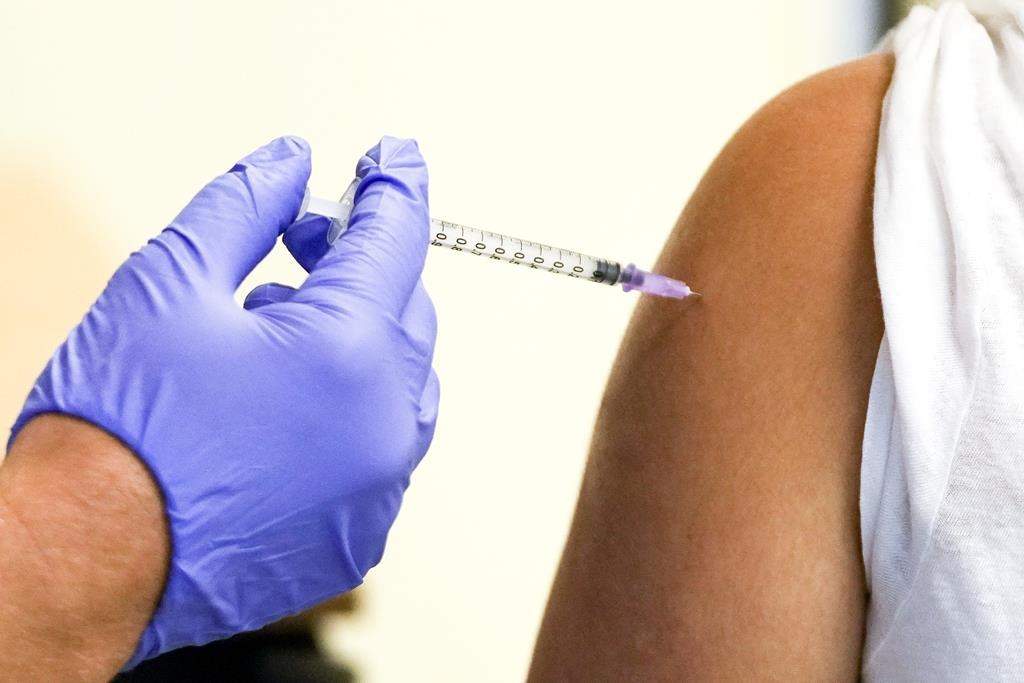 A doctor vaccinates a student in the arm while wearing a purple glove