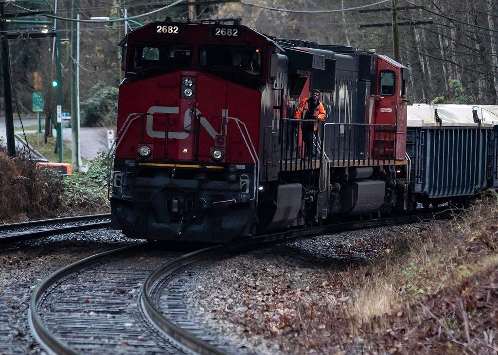 A CN rail worker stands on an idle locomotive as protesters opposed to the Trans Mountain pipeline expansion block rail lines, in Burnaby, B.C., Friday, Nov. 27, 2020. The railway says it will hold a special meeting on March 22 in response to a request by British investor TCI Fund Management which is seeking the election of a slate of new board members and the replacement of the CEO. THE CANADIAN PRESS/Darryl Dyck.