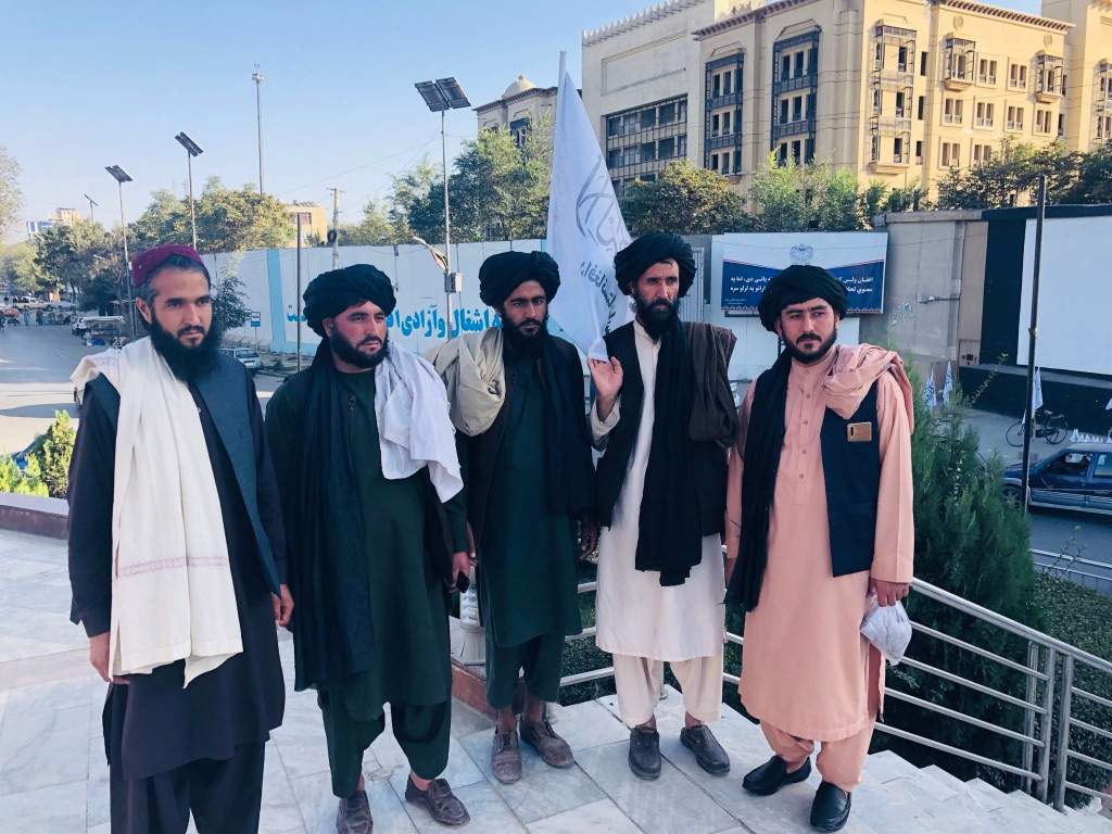Taliban members pose with their flag at Massoud Circle, where portraits of the anti-Taliban fighter Ahmad Shah Massoud have been torn down.