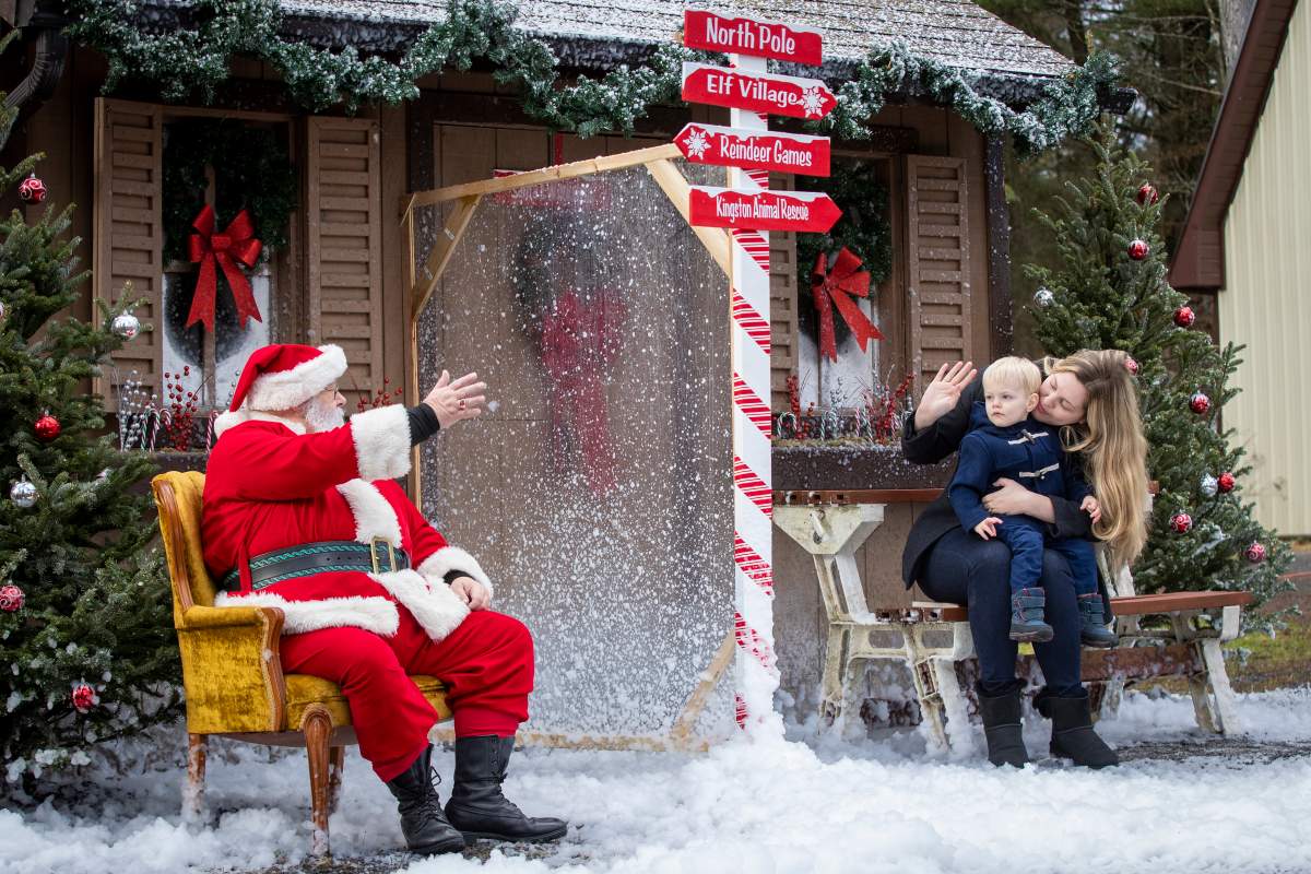 Noah LeClaire and his mother Jennifer Amos wave at Santa through plexiglas during physically distanced visit with Santa in Kingston on Saturday, November 28, 2020. 