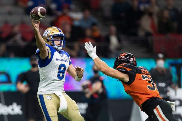 Winnipeg Blue Bombers quarterback Zach Collaros, left, passes over B.C. Lions’ Adam Konar during the first half of a CFL football game in Vancouver, on Friday, October 1, 2021.