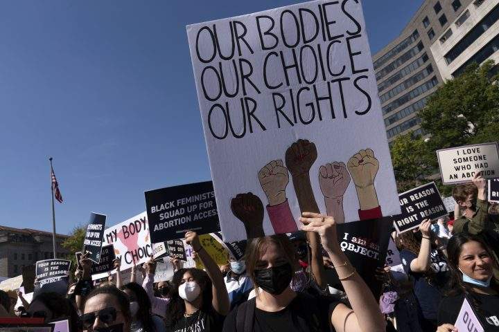 Activists hold signs during the Women’s March rally at Freedom Plaza, in Washington, Saturday, Oct. 2, 2021.