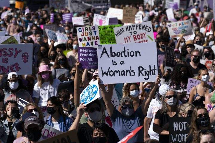 Demonstrators hold signs during the Women’s March rally at Freedom Plaza, in Washington, Saturday, Oct. 2, 2021.