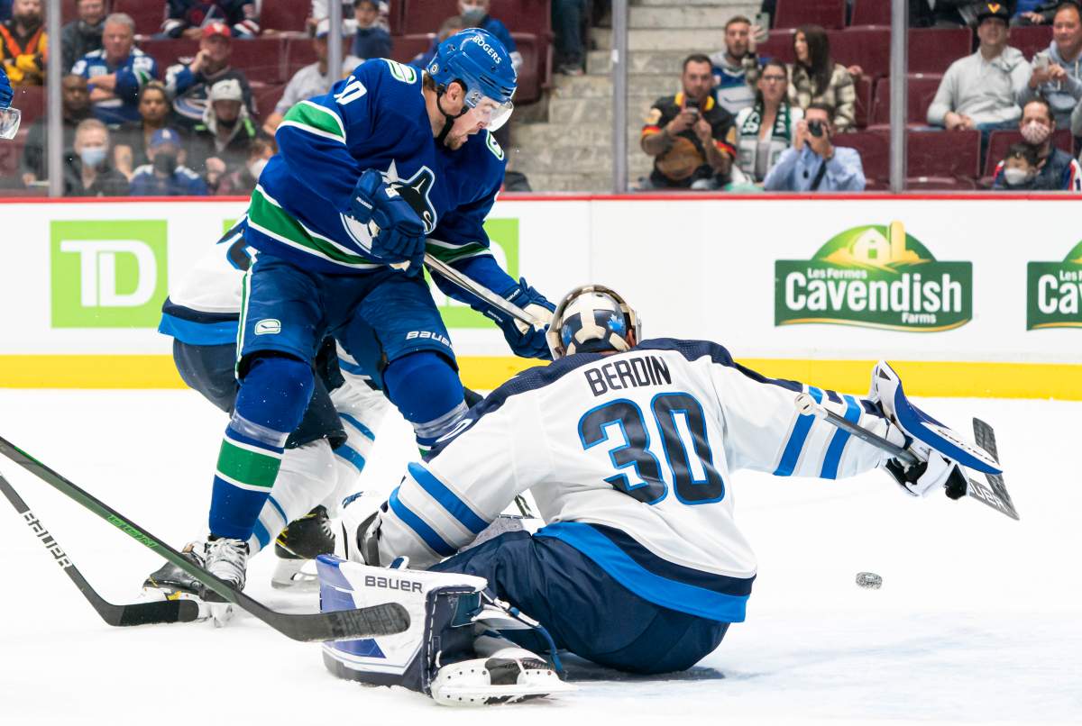 Vancouver Canucks’ Tanner Pearson (left) looks for the loose puck after Winnipeg Jets goalie Mikhail Berdin makes a save during second period NHL preseason hockey action in Vancouver, Sunday, Oct. 3, 2021.