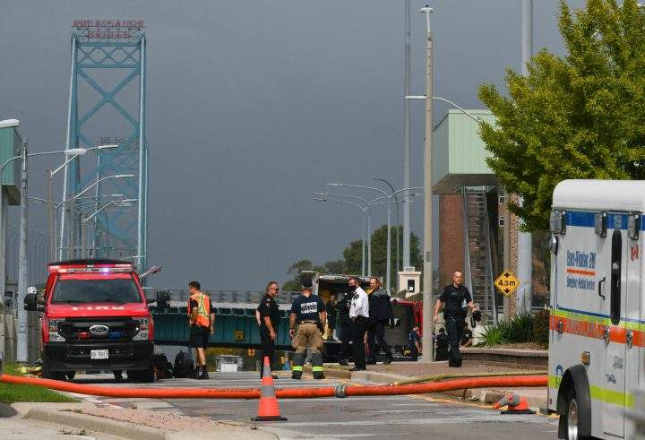 Firefighters and officers look on by the Ambassador Bridge border crossing in Windsor, Ont., Monday, Oct. 4, 2021.