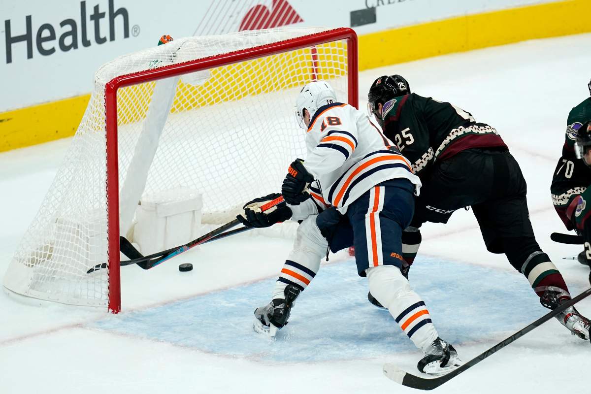Edmonton Oilers left wing Zach Hyman (18) scores a goal, beating Arizona Coyotes defenseman Conor Timmins (25) to the puck during the third period of an NHL hockey game Thursday, Oct. 21, 2021, in Glendale, Ariz. The Oilers won 5-1. (AP Photo/Ross D. Franklin)