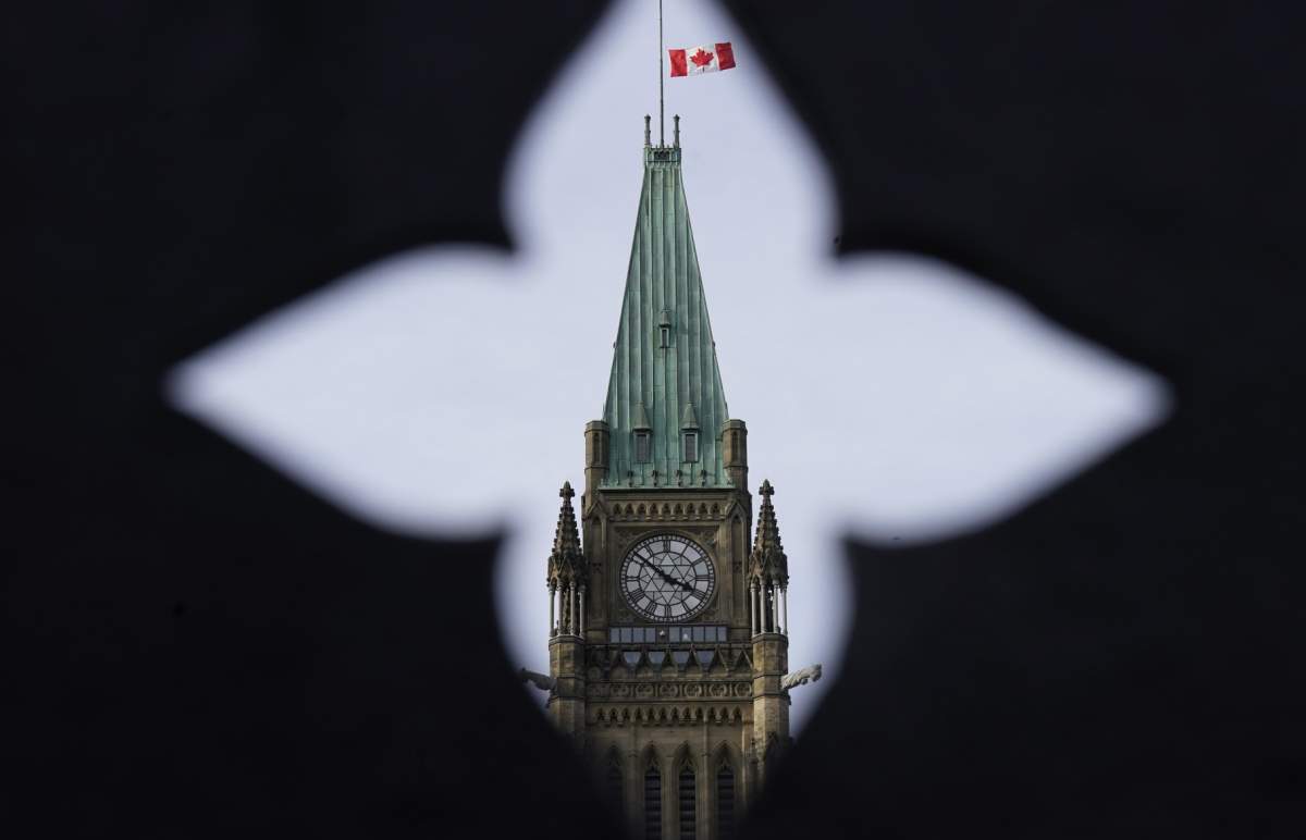 The Canadian flag flies at half mast over the Peace tower and parliament buildings Friday, Oct. 22, 2021.