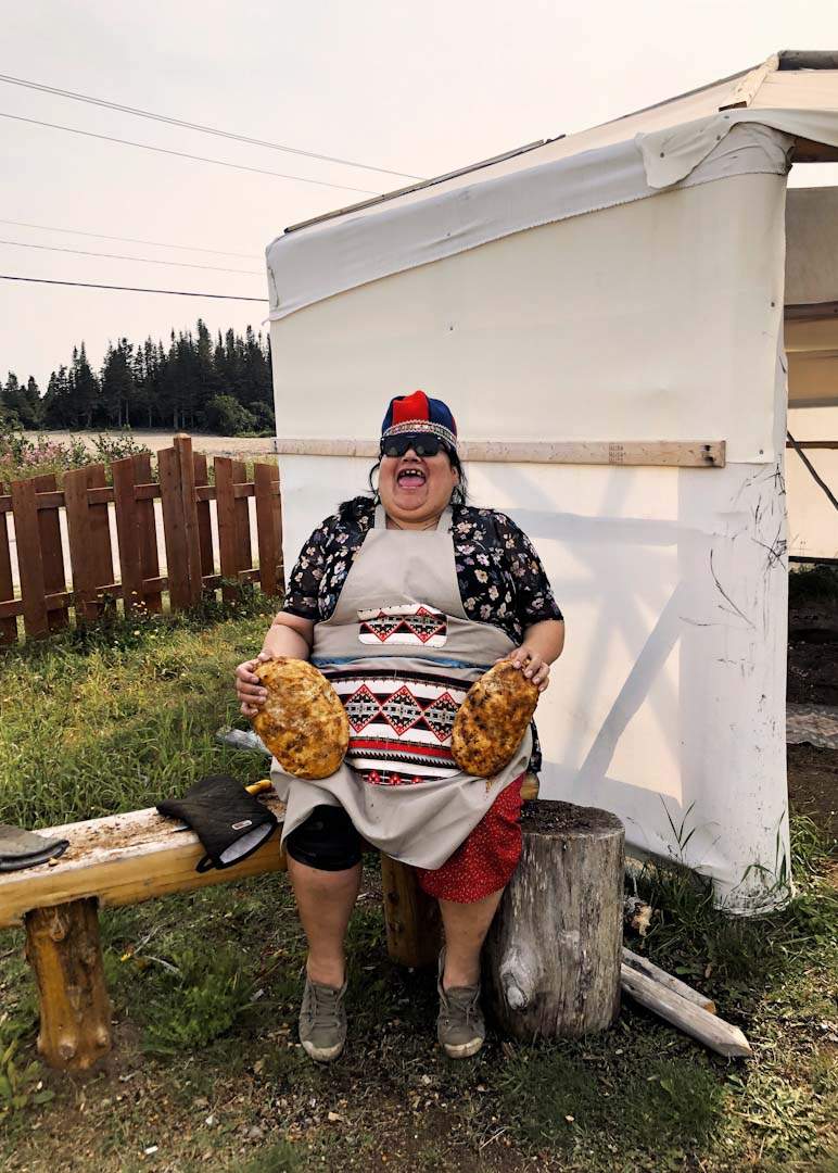 Georgette Mestokosho holds two loaves of bannock that she baked in a sand pit at Ekuanitshit First Nation.