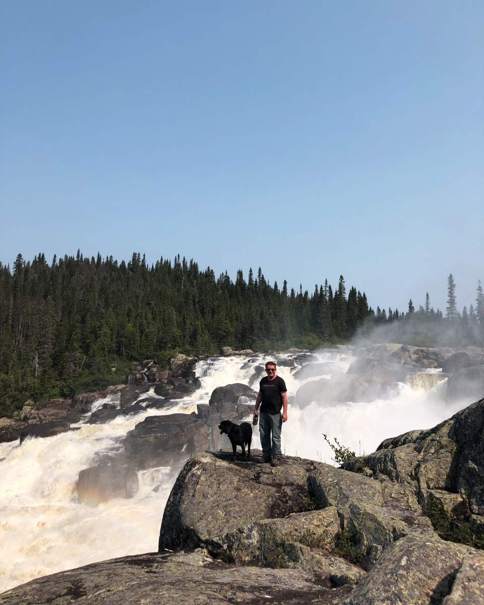 Sylvain Roy and his dog, Katak, stand next to Magpie Falls.