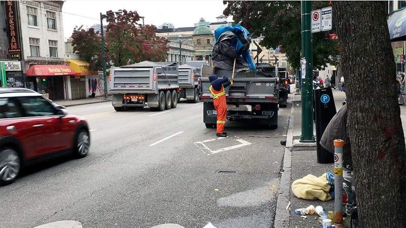 A city worker removes a tent from the sidewalk in Vancouver's Downtown Eastside. 