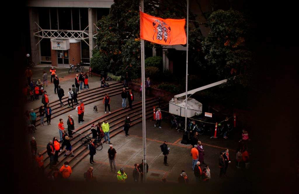 A ceremonial flagged is raised as people attend the Xe xe Smun’ eem-Victoria Orange Shirt Day Every Child Matters ceremony to honour victims of the Canadian Indian residential school system while at Centennial Square in Victoria, Thursday, Sept. 30, 2021.