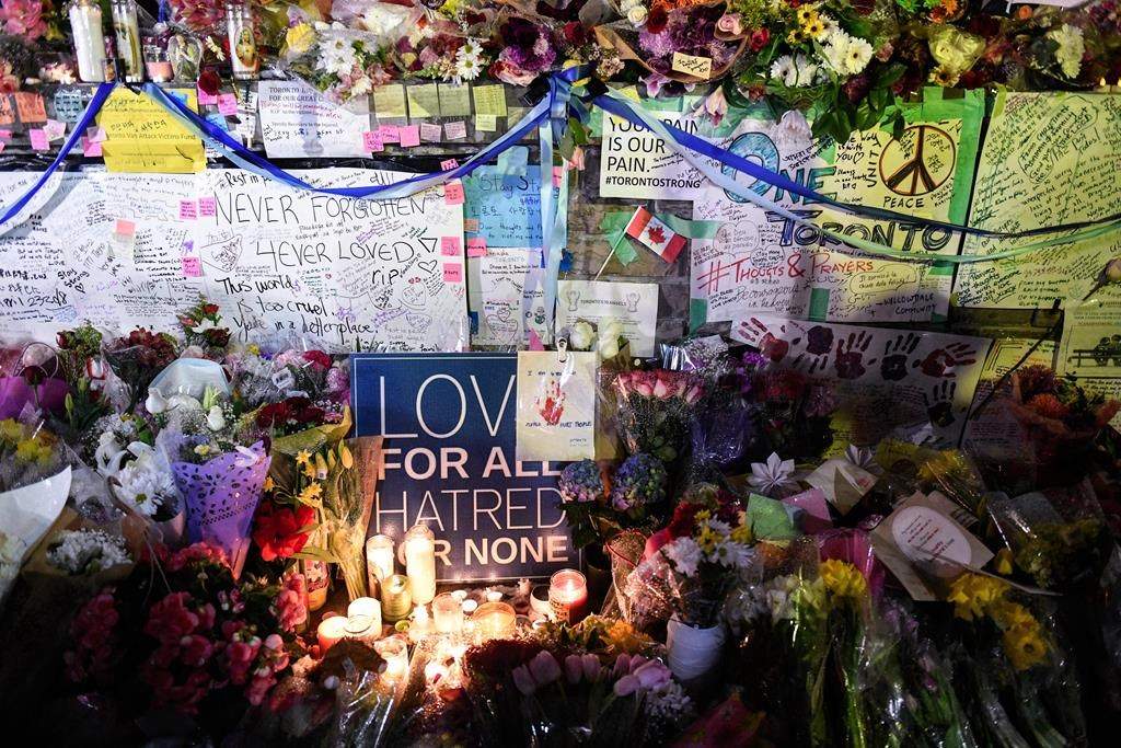 Flowers, notes and candles are piled high at a vigil on Yonge Street in Toronto, Tuesday, April 24, 2018.