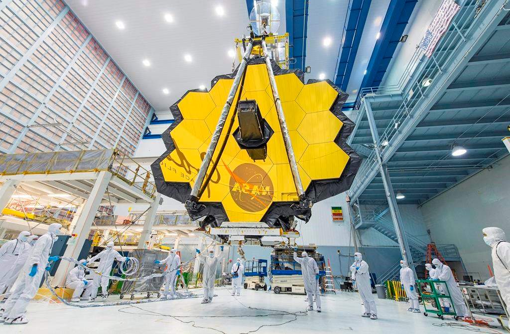 In this 2017 photo made available by NASA, technicians lift the mirror assembly of the James Webb Space Telescope using a crane.