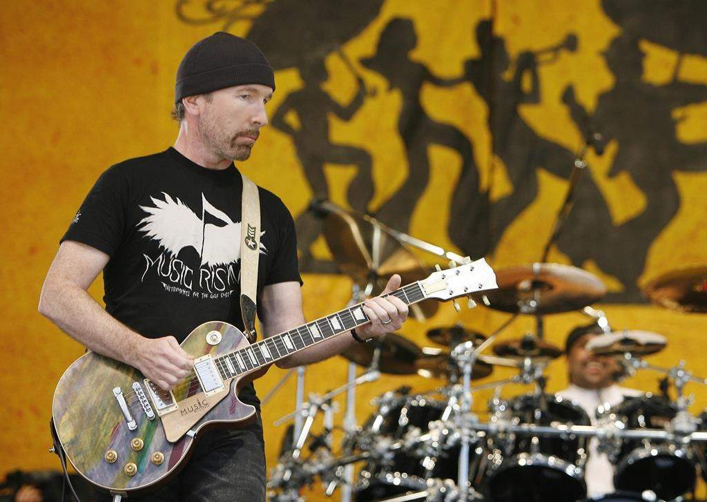 FILE - U2 guitarist The Edge wears a Music First T-shirt as he performs during the New Orleans Jazz and Heritage Festival in New Orleans on April 29, 2006. The Edge and his Music Rising charity will host an auction of rock memorabilia on Dec. 11, 2021 to benefit New Orleans musicians hit hard by the pandemic. Items for sale include what Edge calls his “One” guitar and memorabilia from Alice Cooper and Aerosmith to Pink Floyd and Kiss. (AP Photo/Alex Brandon, File).