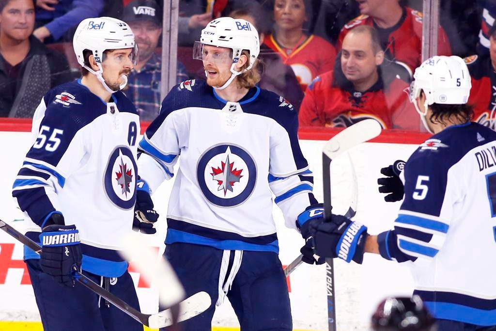 The Winnipeg Jets’ Kyle Connor, centre, celebrates his goal against the Calgary Flames with Mark Scheifele, left, and Brenden Dillon during third-period NHL hockey action in Calgary, Saturday, Nov. 27, 2021. THE CANADIAN PRESS/Larry Mac Dougal