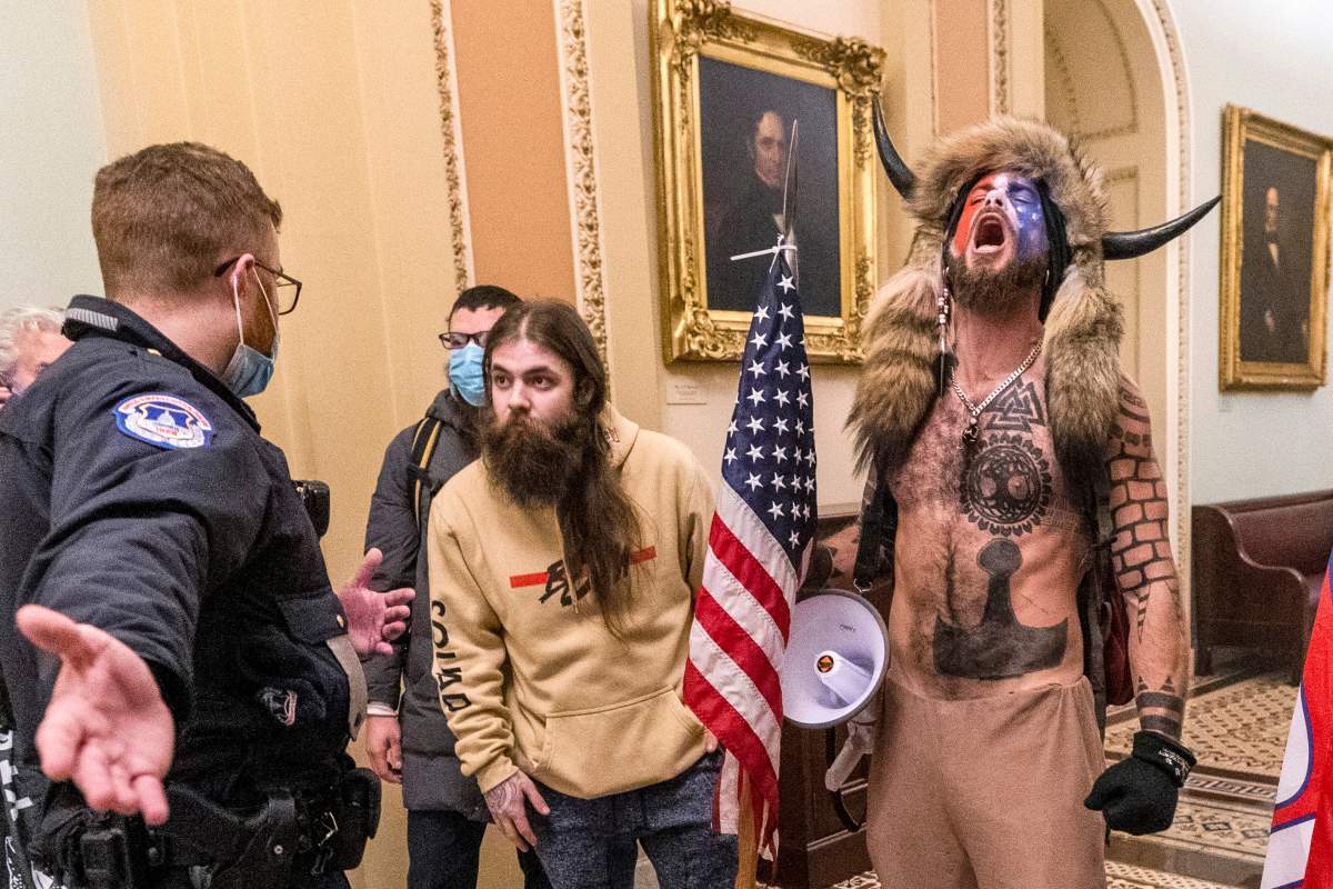 FILE - In this Jan. 6, 2021 file photo, supporters of President Donald Trump, including Jacob Chansley, right with fur hat, are confronted by U.S. Capitol Police officers outside the Senate Chamber inside the Capitol in Washington.