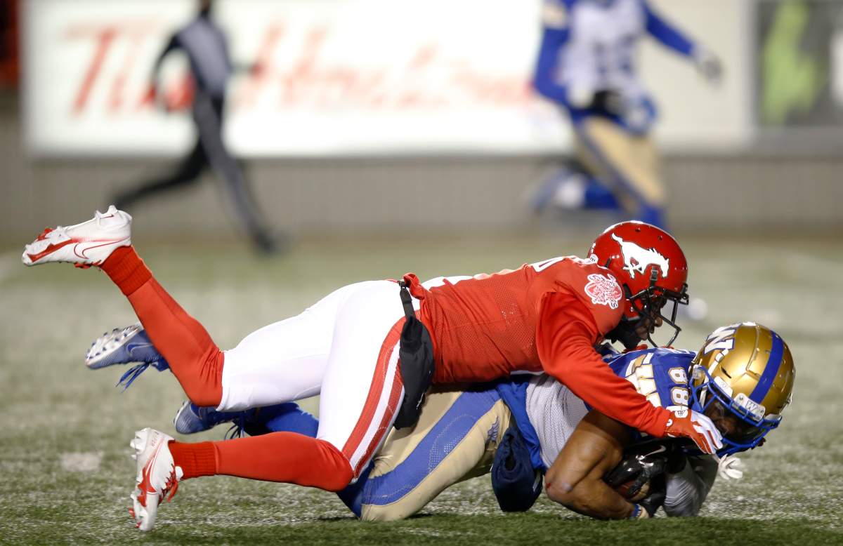 Calgary Stampeders' Richard Leonard, left, tackles Winnipeg Blue Bombers' Rasheed Bailey during the first half of their CFL football game in Calgary, Saturday, Nov. 20, 2021.