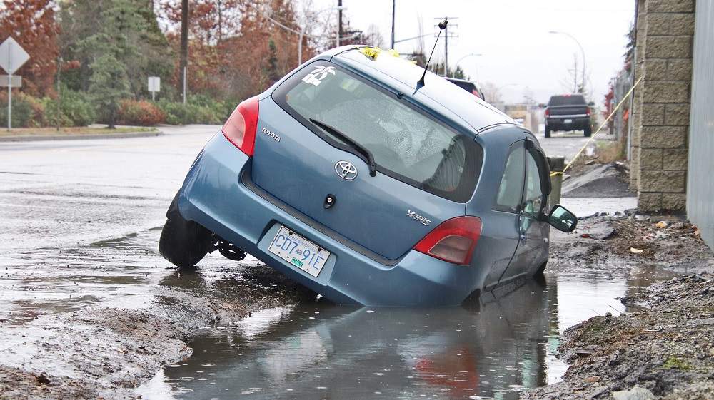 A Toyota Yaris parked along Grace Rd in Surrey ended up in a small sinkhole after the side of the road gave way.