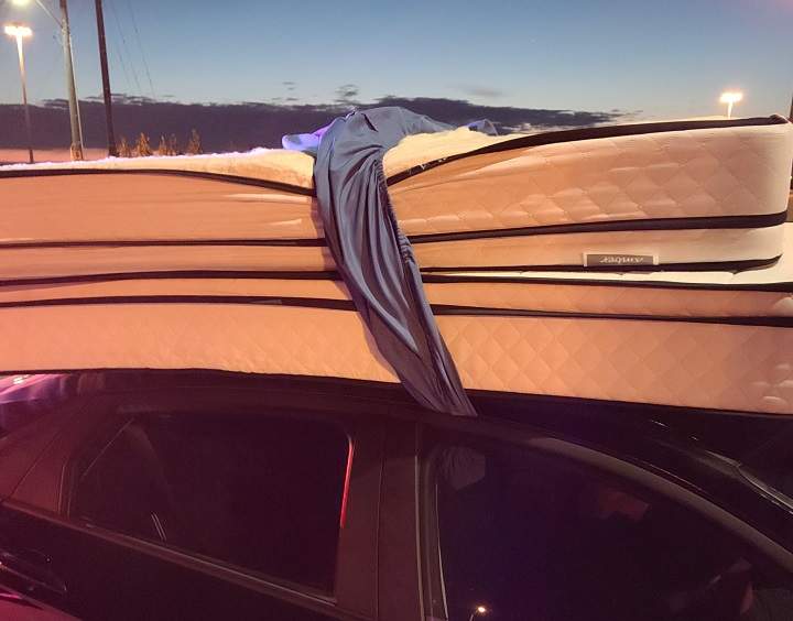 A photo of the vehicle with two mattresses secured by a bedsheet.