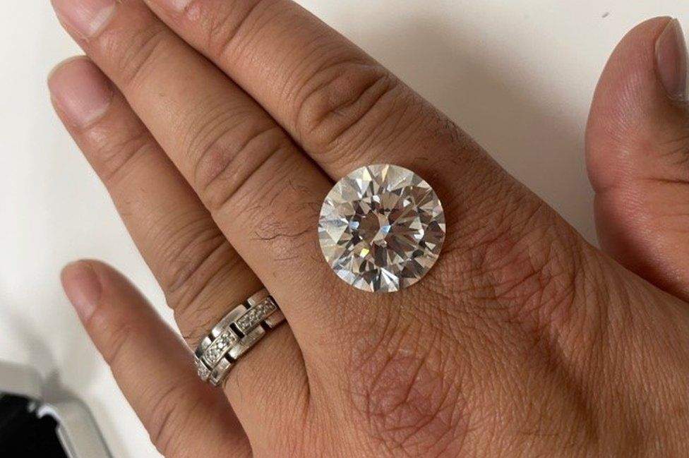 A photo of the diamond, shown between two fingers.